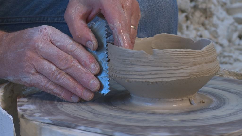 Bruce Dehnert works on one of his sculpturally detailed thrown pots.