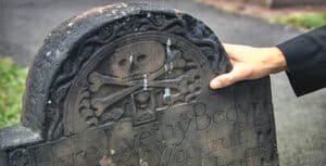 Close-up of a colonial-era gravestone with a skull and crossbones carving